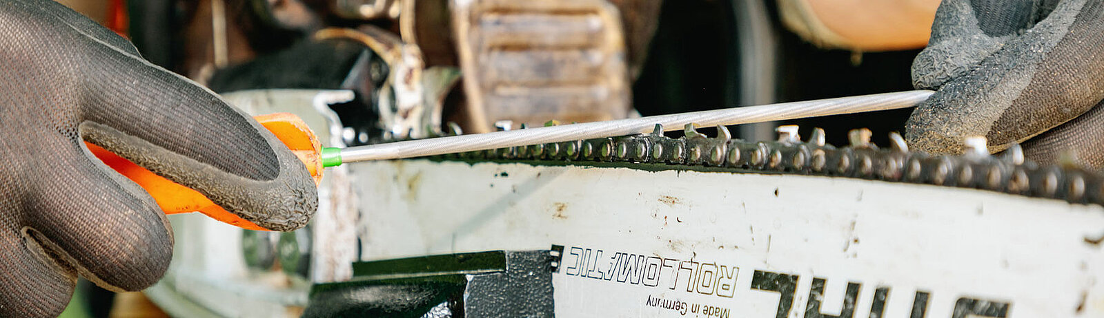Kette einer Motorsäge wird mit einer Feile geschärft